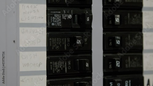 Male electrician turning off power for electrical outlet at circuit breaker box. Resetting Tripped breaker 