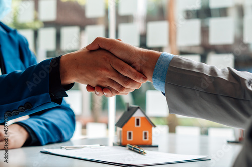 Real estate broker and customer shaking hands after signing a contract: real estate, home loan and insurance concept photo