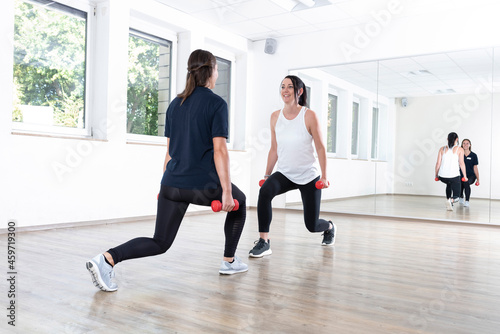 Zwei junge Frauen machen Sport in einer Sporthalle mit Spiegel  Physiotherapie  Bewegungstherapie