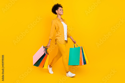 Full length body size photo woman walk with packages on sale isolated vivid yellow color background