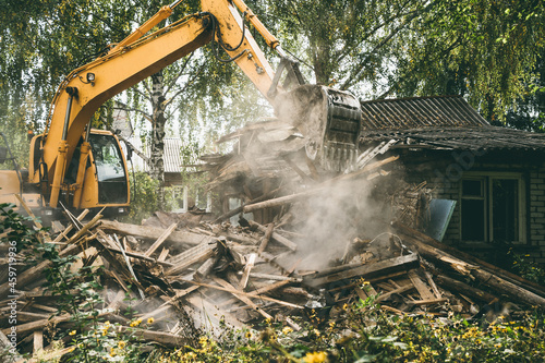 Demolition of old house. Excavator breaks building. City development, construction of new housing on site of old.