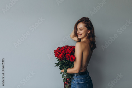 Beauty woman nude with red roses on grey background. Sensual pretty brunette woman portrait