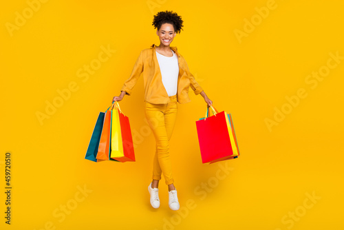 Full length body size photo woman jumping with bag in shopping center isolated vibrant yellow color background