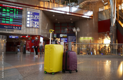Two suitcases stand in the lobby of the train station against the background of the waiting room and against information panel at airport or train station.Vacation and travel concept.