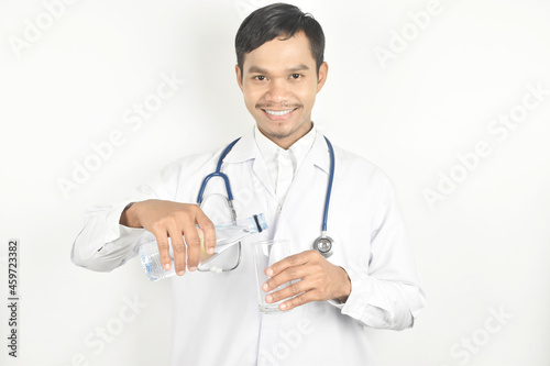 Doctor pouring water out of a bottle into a glass on white background.
