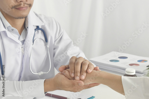 Close up of doctor hand reassuring her female patient at hospital. Doctor holding hands of patient. Physician consulting his patient.