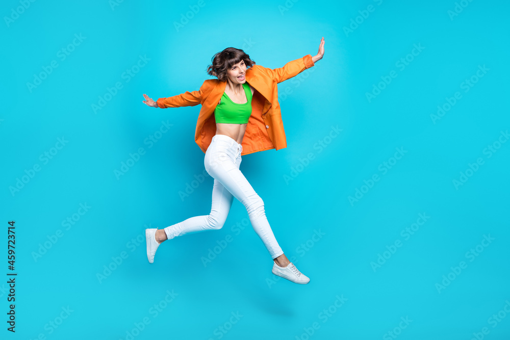 Full size photo of cheerful happy young woman jump up enjoy good mood active isolated on blue color background