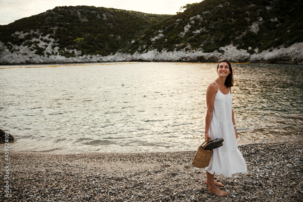 Caucasian female walking along the beach holding sandals Caucasian female walking along the beach holding sandals