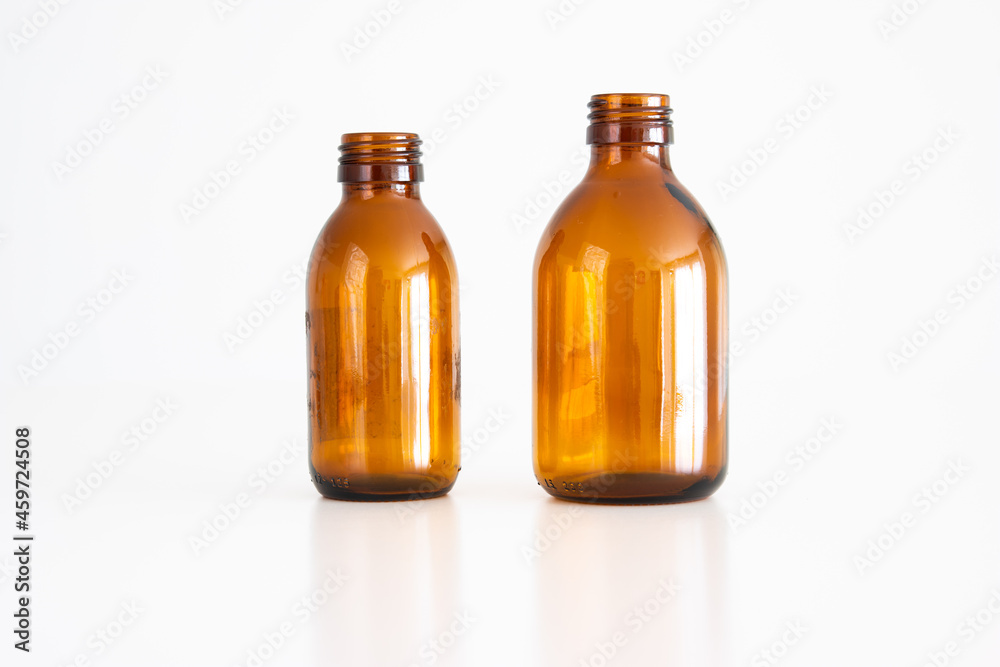2 empty brown glass medical bottles with no cap on. Close up studio shot, isolated on white background