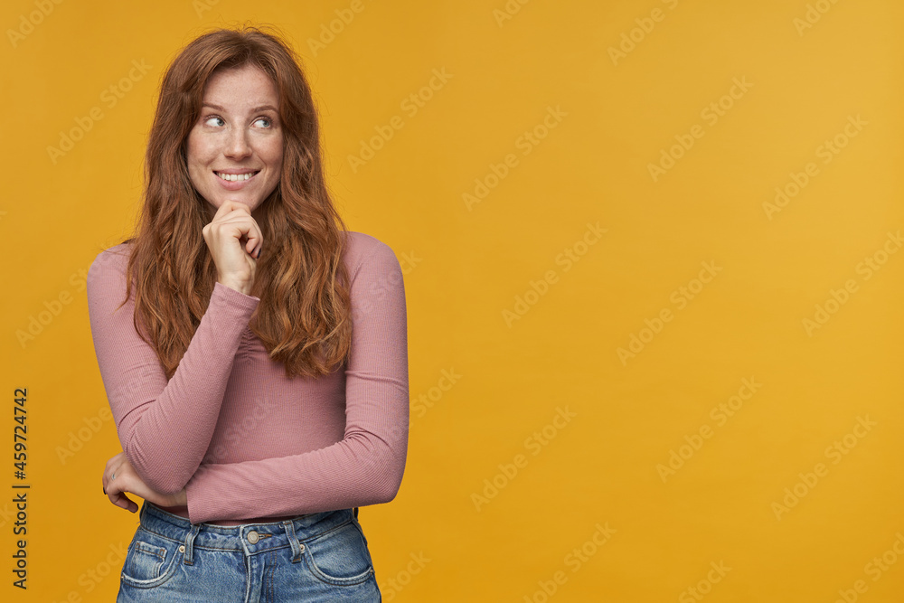 Indoor shot of young ginger woman, with wavy hair and freckles, looks aside at copy space, have dreams or thoughts, isolated. Indoor shot of young ginger woman, with wavy hair and freckles, looks aside at copy space, have dreams or thoughts, isolated.