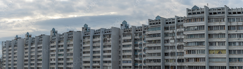 Bottom view of a multi-storey panel residential building on dramatic sky background. City life view.