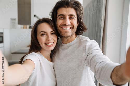 Young multiracial couple smiling and hugging while taking selfie photo