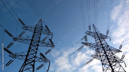 Two power lines under blue skies and fast moving white clouds.  b roll