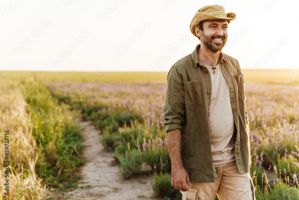 White bristle man in hat smiling while working in farm field White bristle man in hat smiling while working in farm field