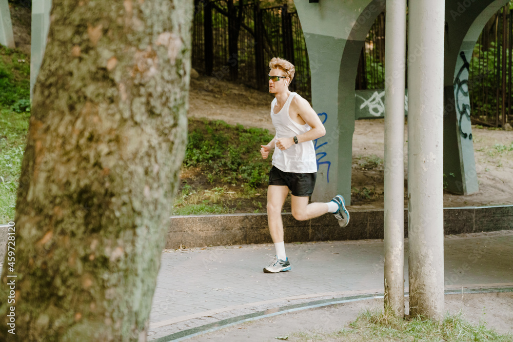 Young sportsman running while working out on green park Young sportsman running while working out on green park