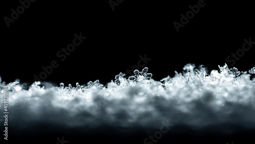 Natural snow texture with snowflakes close-up on the window, isolated on black background. Blank for holiday gift cards. Macro texture of snow, snowflakes.