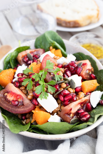 Lentil salad with pumpkin, tomatoes, pomegranate seeds, spinach and goat cheese. Refreshing legume and vegetable salad. Vegetarian food photography 