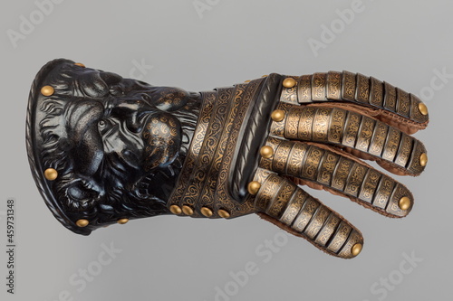 Foto Medieval knightly brown plate gauntlet from Italian armor, in the form of a lion's face and mane, period of the 16th century, on a light background