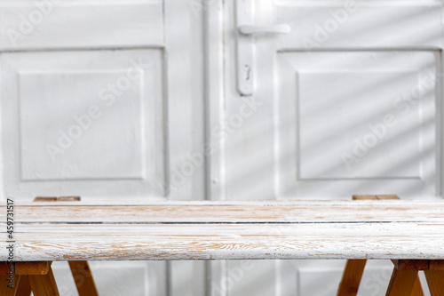 Wooden white table against a background of white doors with a lift on a beautiful warm day