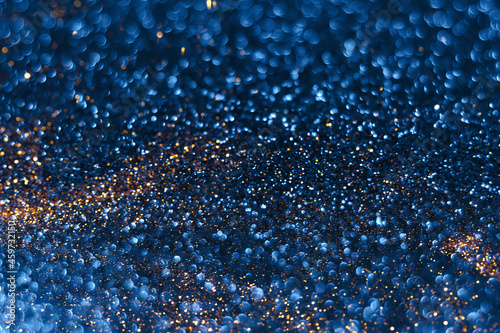 Blue and golden sparkling glitter bokeh background, christmas abstract defocused texture. Holiday lights