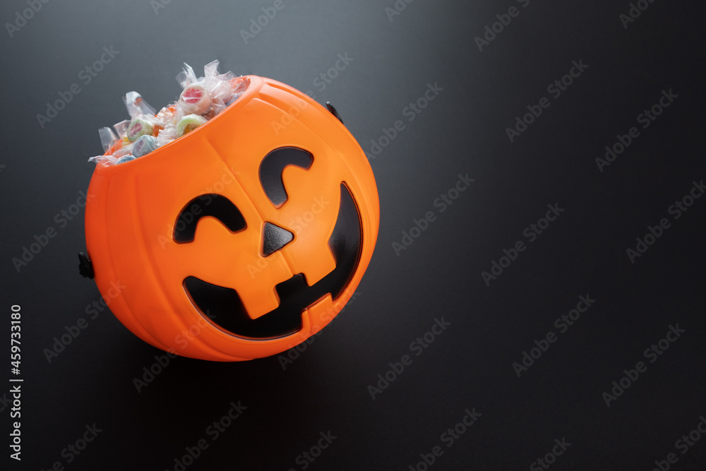 Fototapeta premium halloween sale, pumpkin candy bowl with lollipops,copy space,black background