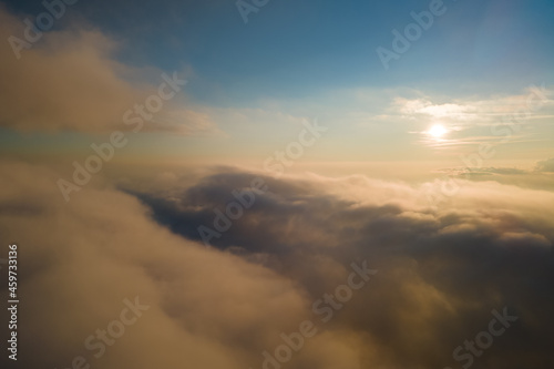 Aerial view from airplane window at high altitude of dense puffy cumulus clouds forming before rainstorm in evening.