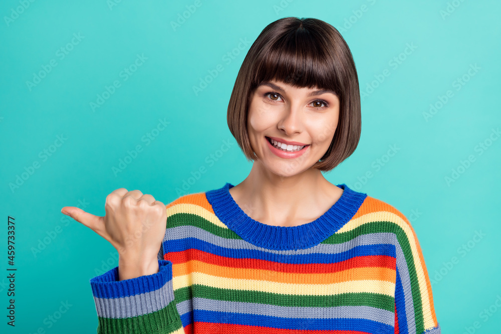 Photo of young woman happy positive smile point thumb empty space ad promo sale isolated over turquoise color background Photo of young woman happy positive smile point thumb empty space ad promo sale isolated over turquoise color background