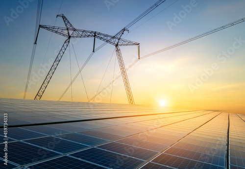 Carta da parati High voltage pylons with electric power lines transfering electricity from solar photovoltaic sells at sunrise