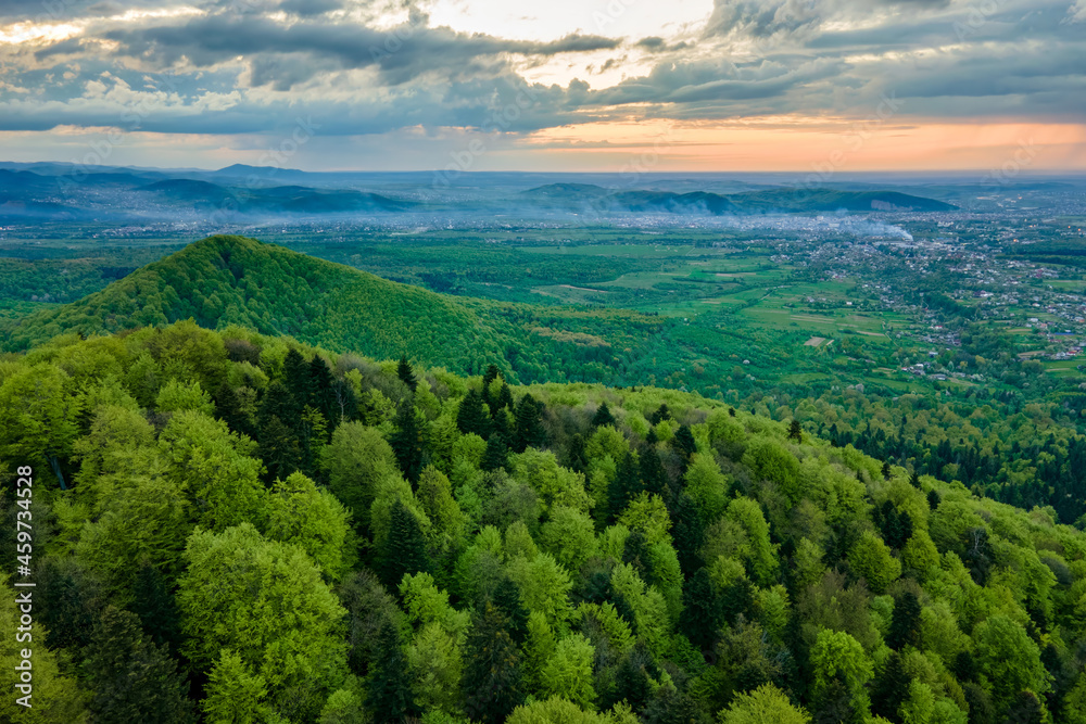 Aerial view of dark mountain hills covered with green mixed pine and lush forest in evening.