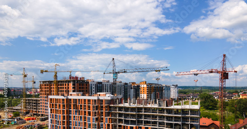 Tower crane at high concrete residential building under construction. Real estate development concept.