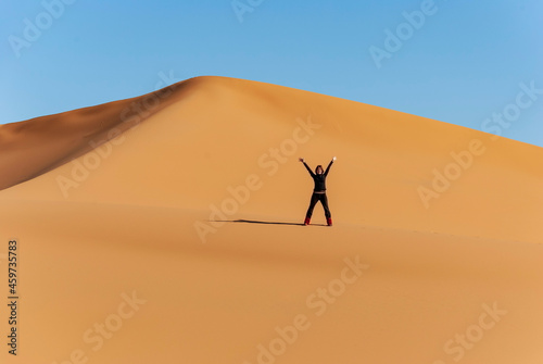 girl waving to the camera on the desert dune on a sunny day