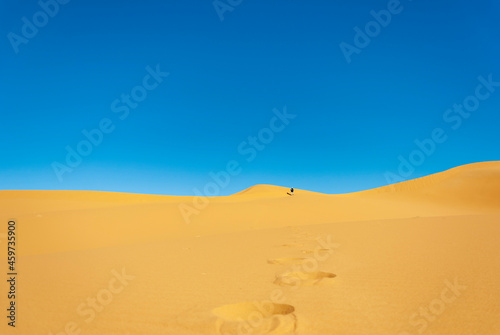 man walking in the desert dunes