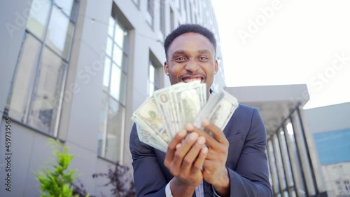 Happy successful African American businessman counts, waves, throws, show off, flaunt, cash money background a modern office building looking at camera Celebrate Winner success in betting stock market