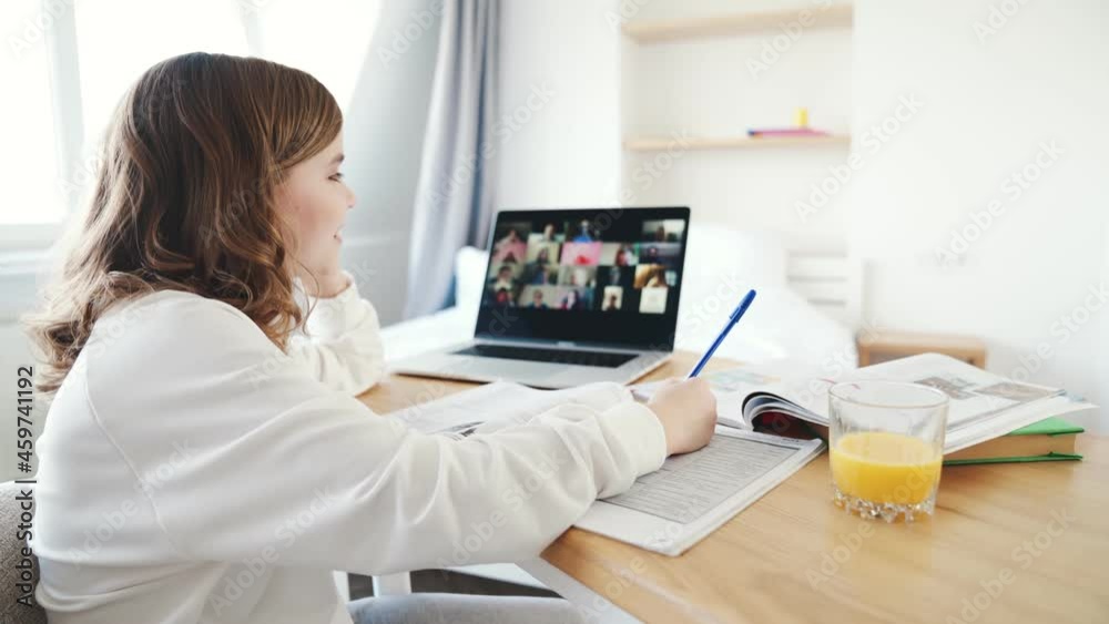 A side view of the handsome little girl taking a part in the online lesson and making a thumb-up gesture A side view of the handsome little girl taking a part in the online lesson and making a thumb-up gesture