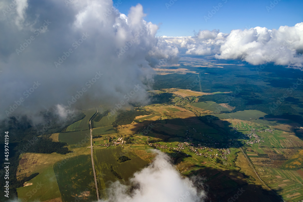 Aerial view from airplane window at high altitude of earth covered with white puffy cumulus clouds.