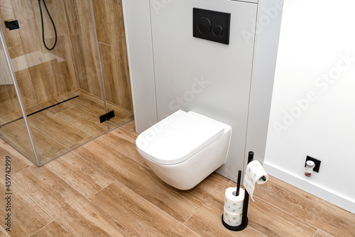 Leinwand Poster A white ceramic toilet with an closed flap in a modern bathroom, a floor covered with ceramic tiles imitating wood