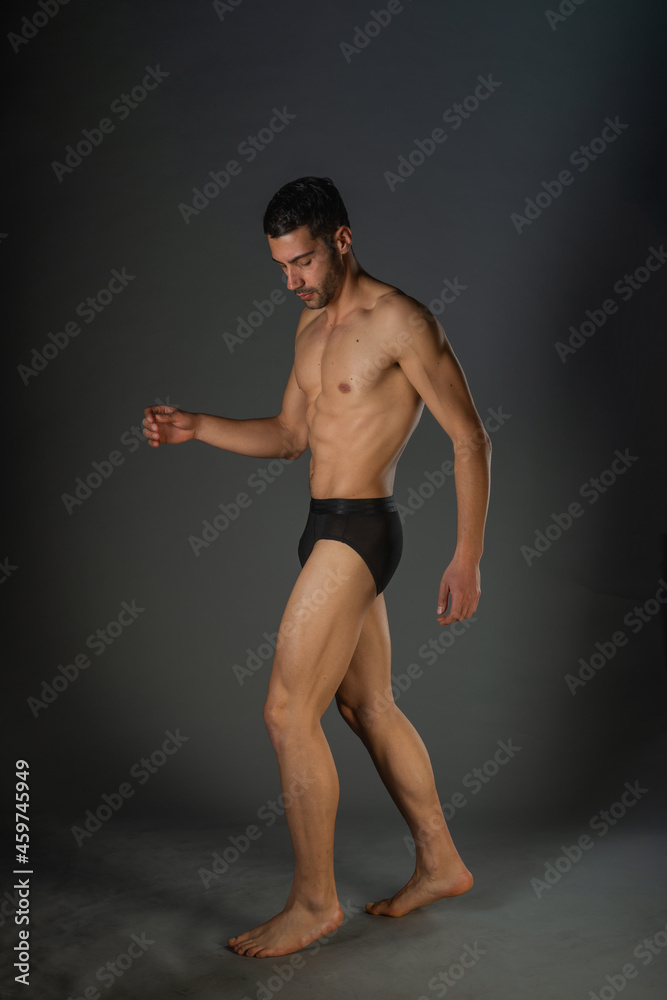 Naklejka premium Sexy man with a muscular body posing naked with black underpants inside a studio
