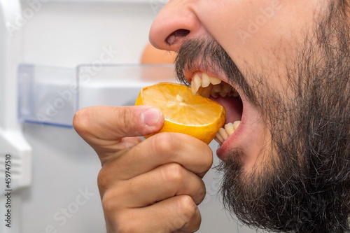Wallpaper Mural A bearded man on the background of an open refrigerator bites a lemon Torontodigital.ca