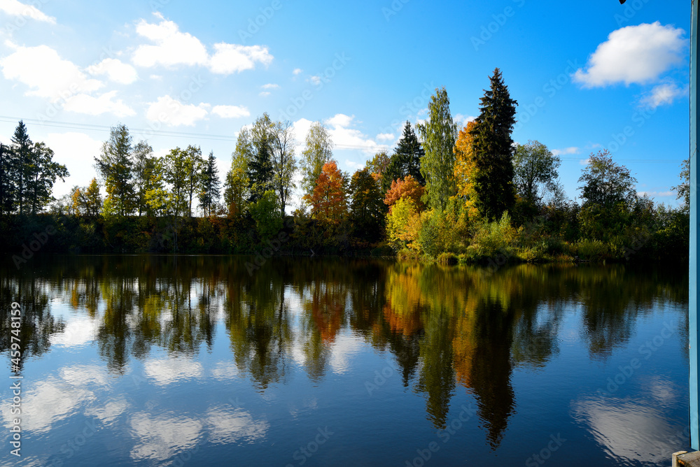 a beautiful golden autumn reflection in a lake with different colored trees and blue skies