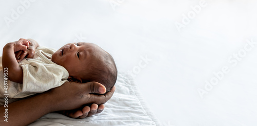 Baby black skin newborn son is 12-day-old lying on the hand of father with happy, On white background and space, concept to African family and black skin newborn