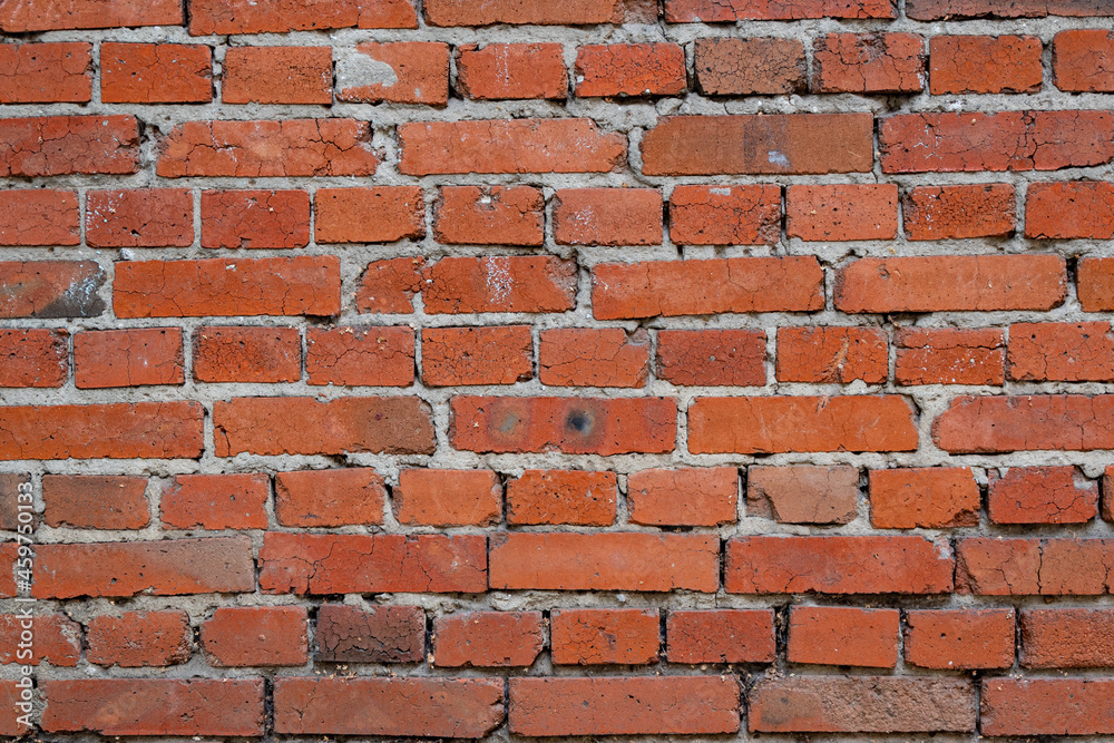 Obraz premium Photo of the texture of a brick wall, made of red clay bricks with inflows of cement mortar and uneven brickwork.