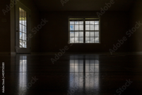 A very dark and almost black room with the only light coming in through the window and door window