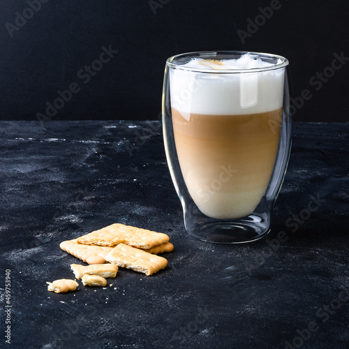 Transparent glass with cappuccino coffe and milk foam