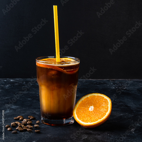 Glass of tasty coffee with orange juice on dark background