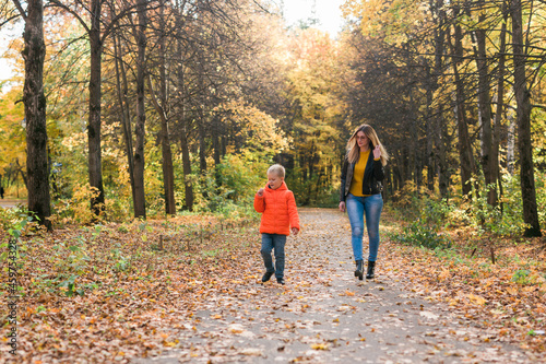 Mother and son walking in the fall park and enjoying the beautiful autumn nature. Season  single parent and children concept.