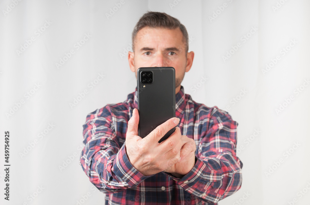 Senior man making photo with smartphone on gray background. Front focus Senior man making photo with smartphone on gray background. Front focus