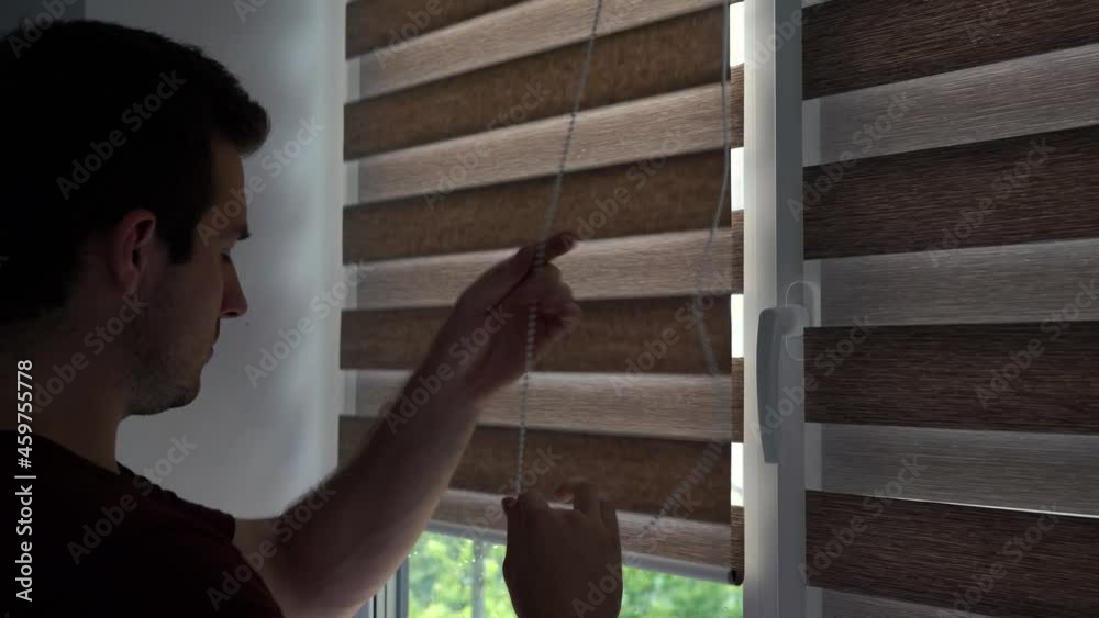 a man opens the blinds in his room in the morning at dawn a man opens the blinds in his room in the morning at dawn