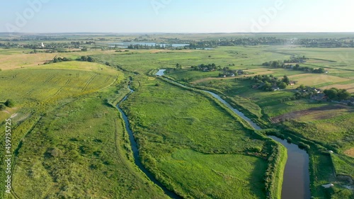 Flying over a small river and a green field