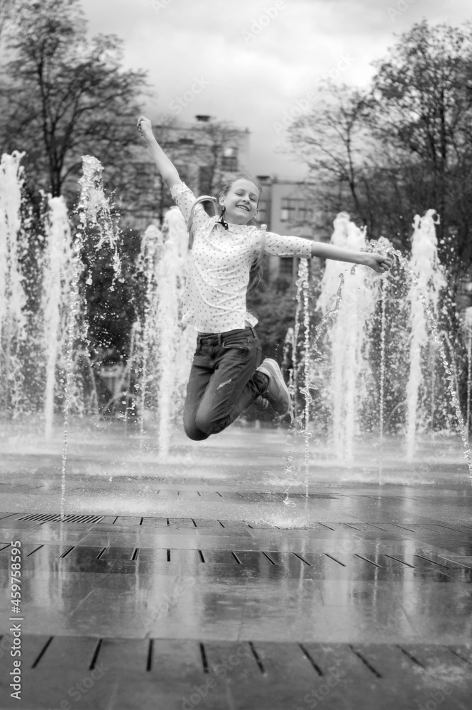 Fototapeta premium Girl and dry fountain. Childhood. Jump in the fountain, black and white photo.