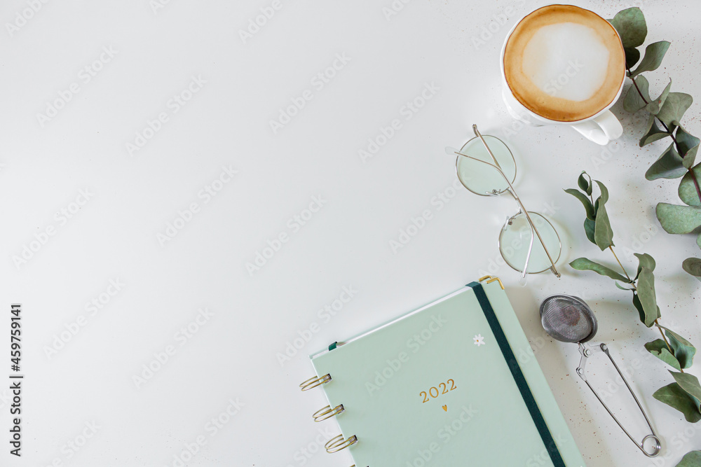 Planner, cup of coffee and milk, eucalyptus leaves, glasses, tea strainer on white background. Flat lay, top view, copy space. Planner, cup of coffee and milk, eucalyptus leaves, glasses, tea strainer on white background. Flat lay, top view, copy space.